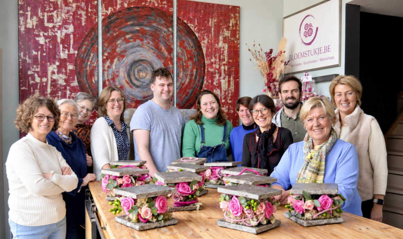 Deelnemers aan een workshop bloemschikken bij Bloemstukje.be met hun roze bloemcreaties.